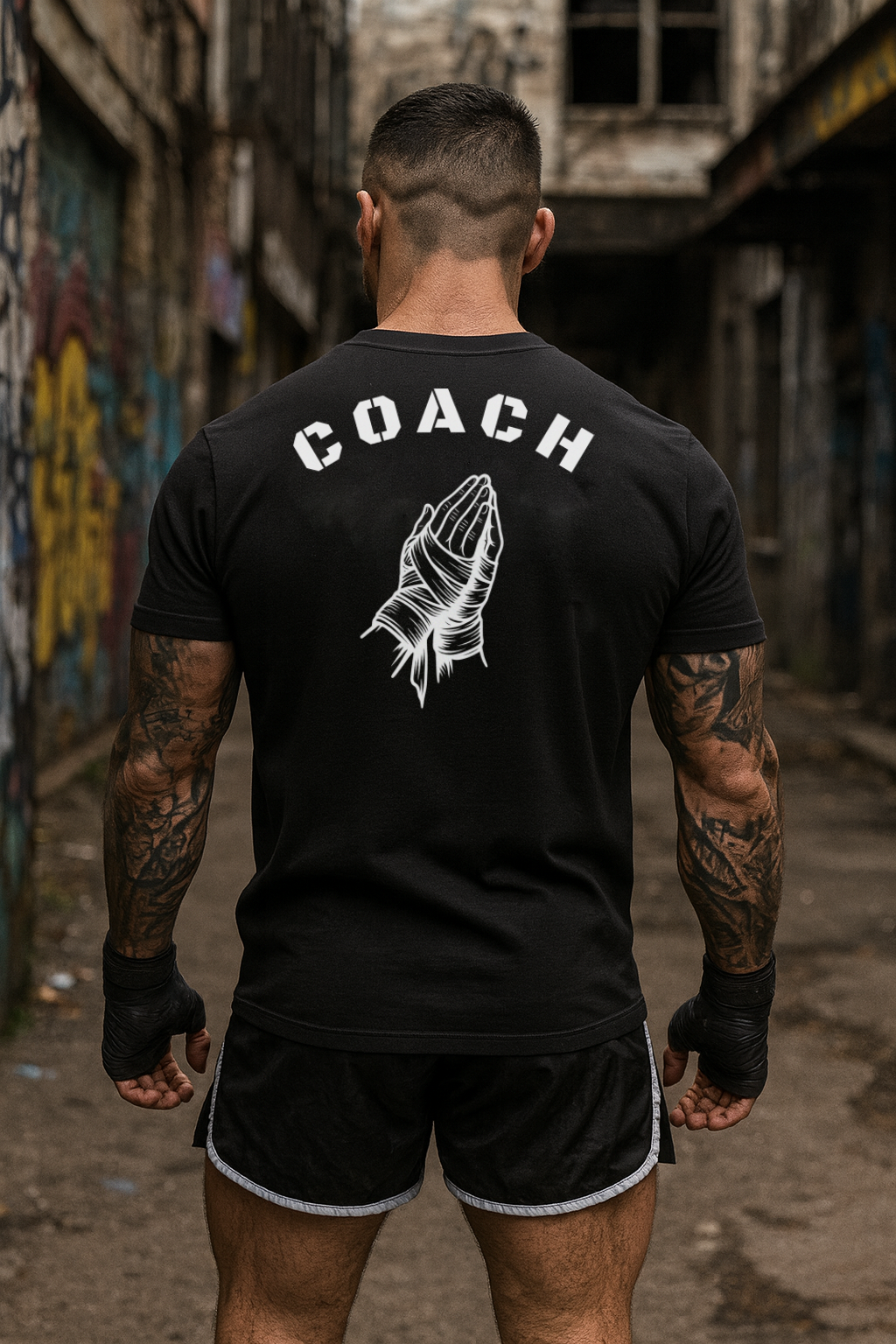 Person wearing a black 'COACH' t-shirt with a graphic design in an urban setting.