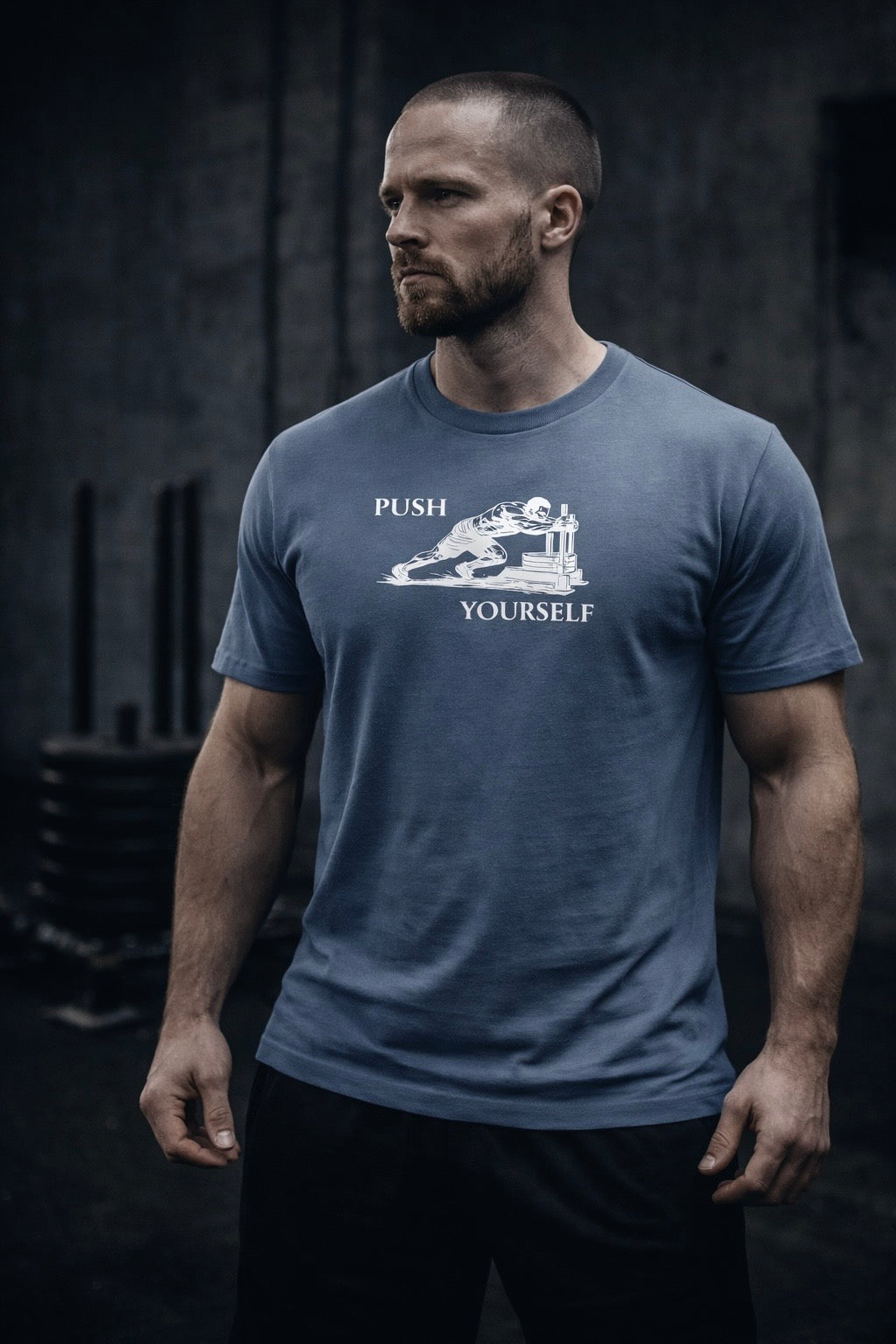 Man wearing a blue t-shirt with 'Push Yourself' graphic in a gym setting