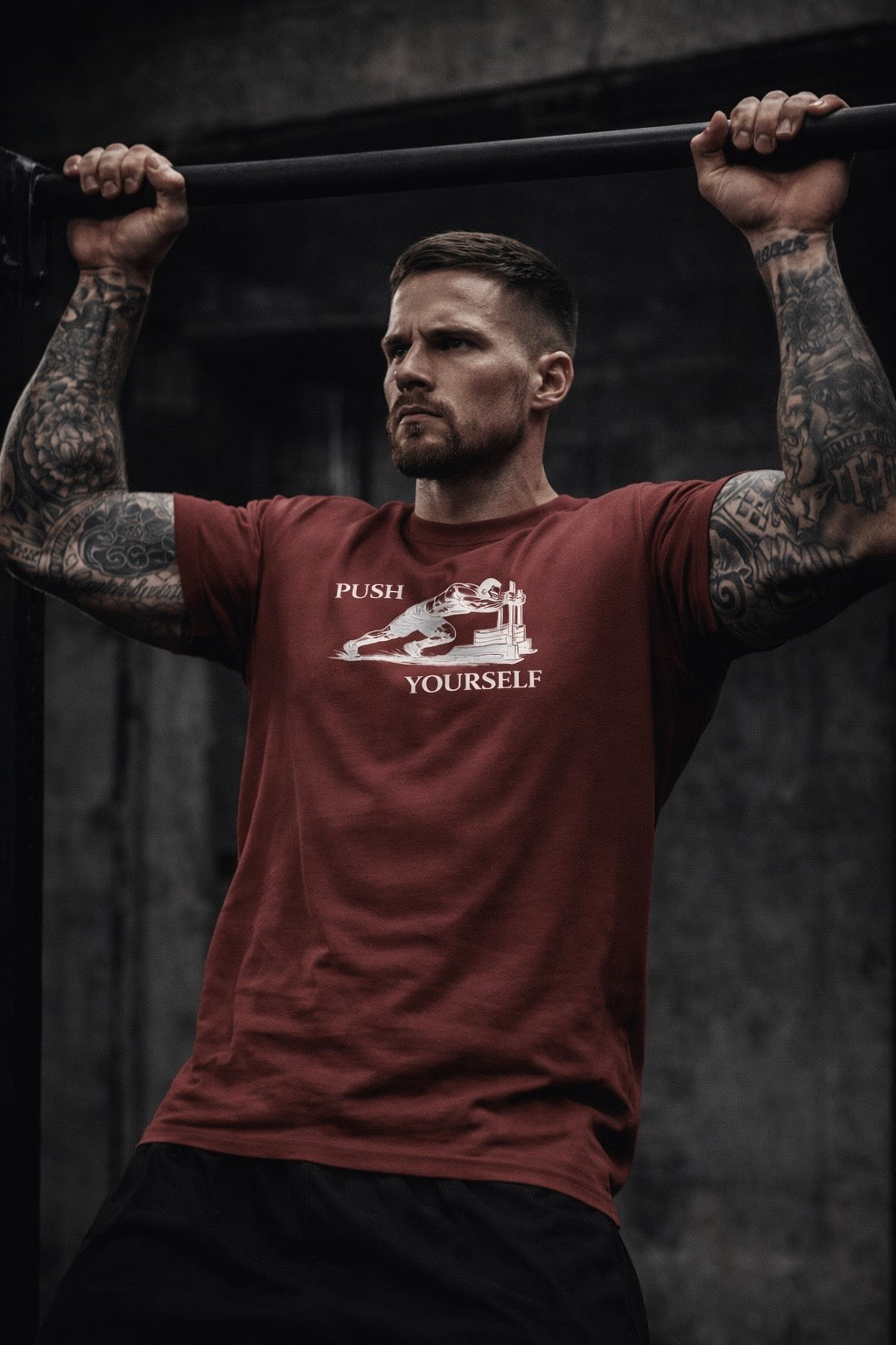 Man lifting weights with a 'Push Yourself' t-shirt on a dark background