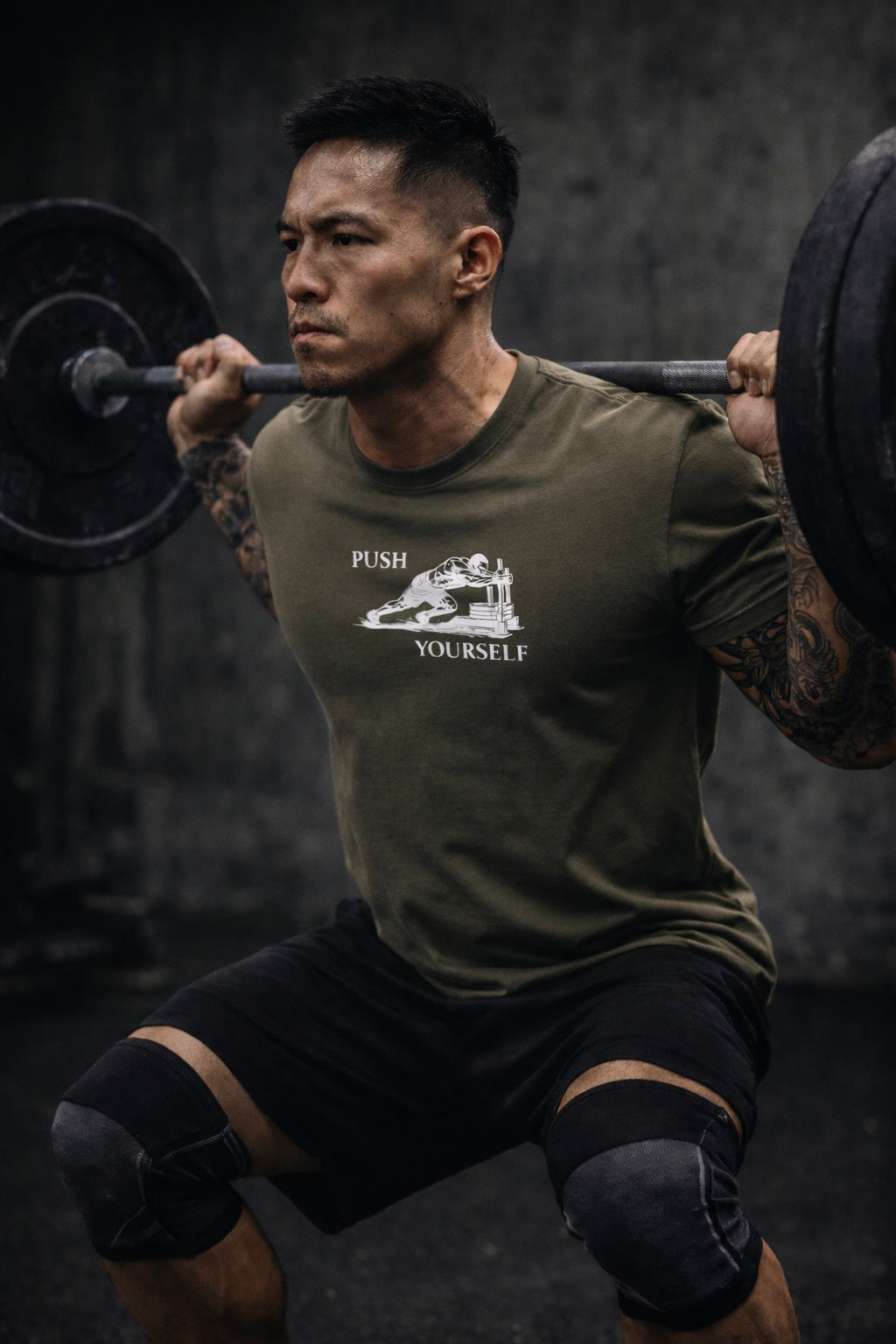 Person lifting a barbell wearing a green t-shirt with 'Push Yourself' text and graphic.