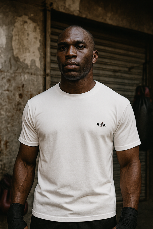 Man wearing a white t-shirt with a logo against a textured wall.
